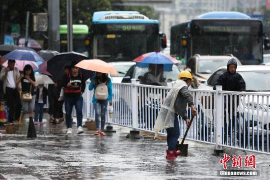 资料图：行人在雨中出行。 黄芷昕 摄