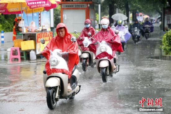 资料图：6月16日，广西柳州市遭暴雨侵袭，民众穿着雨衣骑电动车出行。 记者 朱柳融 摄