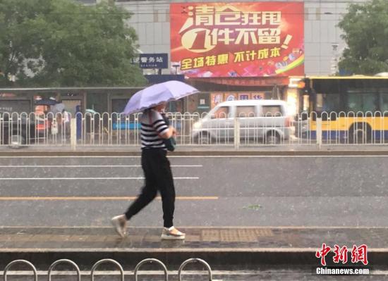 6月23日清晨，北京降雨持续，并出现了短时大雨。据北京市气象局官方微博消息，北京市气象台今日6时发布：今天白天小到中雨并伴有雷电，傍晚局地伴有短时大风或冰雹，北转东风2、3级，最高气温24℃；夜间有雷阵雨，东转北风2、3级，最低气温19℃。图为北京阜成门，一位市民撑伞出行。 记者 富宇 摄